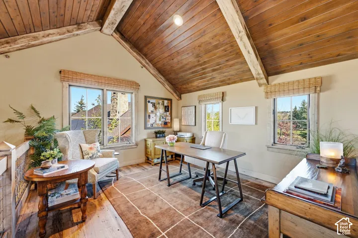 Vaulted ceilings with exposed timber beams and wood-paneled accents, multi-pane windows with woven shades, and wood-finish flooring