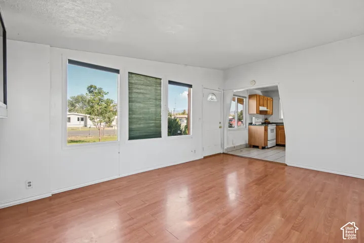 Living area featuring wood-finish flooring, large windows, and a segmented entryway leading to the kitchen