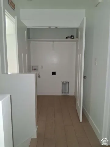Dedicated laundry area featuring double-door closet entry, integrated shelving, wood-finish flooring, and designated utility hookups
