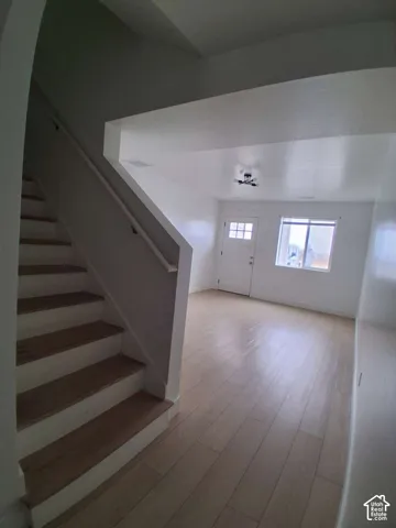 Interior space featuring wood-finish flooring, a wooden staircase, high ceilings, a multi-pane door, and a flush-mount light fixture