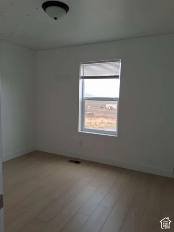 Neutral-toned walls, wood-finish flooring, and a single-hung window with horizontal blinds and an exterior mountain backdrop