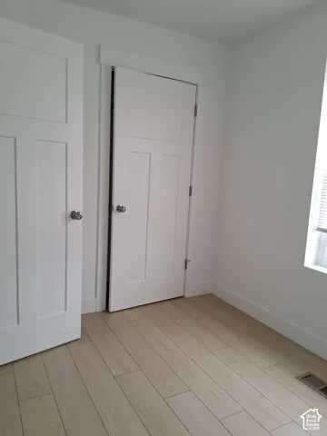 Interior featuring wood-finish flooring, three-panel interior doors, and crisp white trim