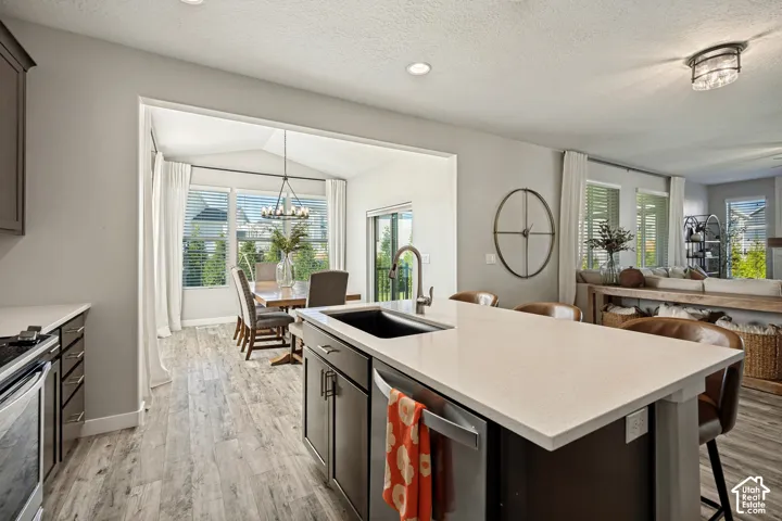 Kitchen featuring a central island with a stone-finish countertop and dark-toned cabinetry, a deep undermount sink, recessed lighting, and wood-finish flooring