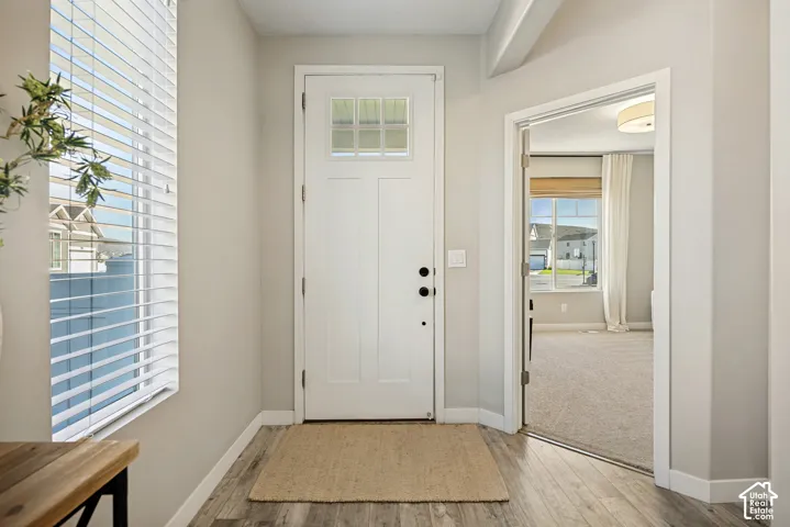 Entryway featuring a white door with a six-pane window insert, wood-finish flooring, and crisp neutral wall tones