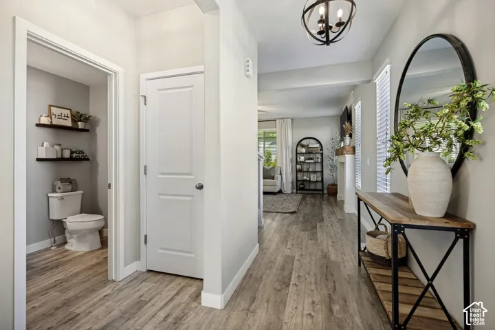 Wood-finish flooring throughout, sphere-style orb chandelier, and wall-mounted wooden shelving in the half-bathroom