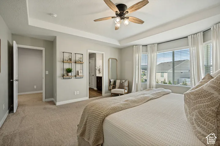Tray ceiling featuring a central multi-blade ceiling fan with integrated lighting and a bay window configuration