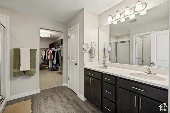 Dual-sink vanity with dark-finish cabinetry, solid-surface countertop, five-light overhead fixture, and large wall-mounted mirror
