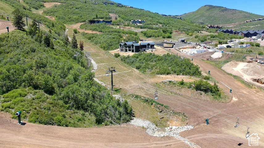Mountain landscape featuring dense vegetation, sloped terrain, and proximity to chairlift infrastructure