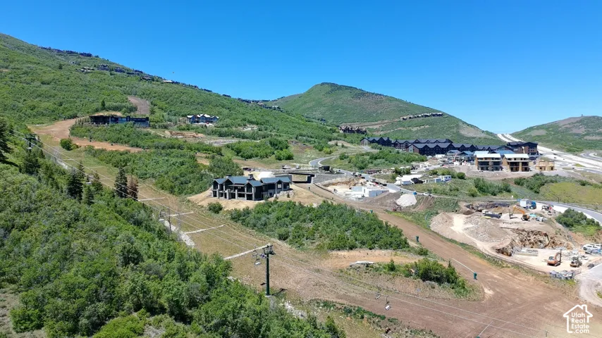 Aerial perspective of mountain landscape featuring ski slope access, mature vegetation, and elevated terrain