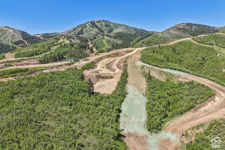 Expansive mountain terrain featuring rolling hills, native vegetation, and dirt access paths