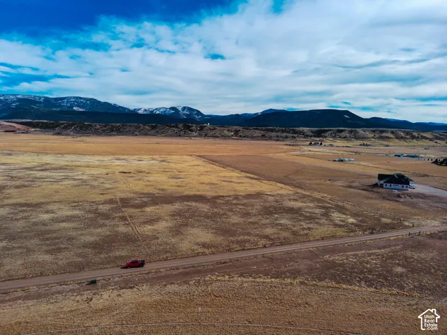 Expansive acreage featuring open terrain, a gravel access road, and prominent mountain backdrops