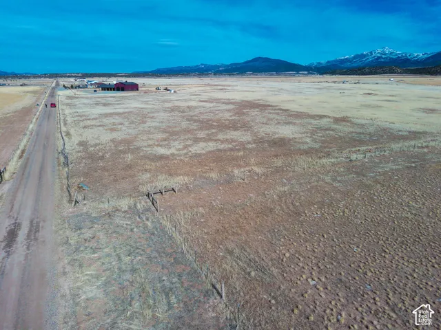 Expansive acreage featuring wire fencing, a metal-sided structure, and prominent mountain range scenery