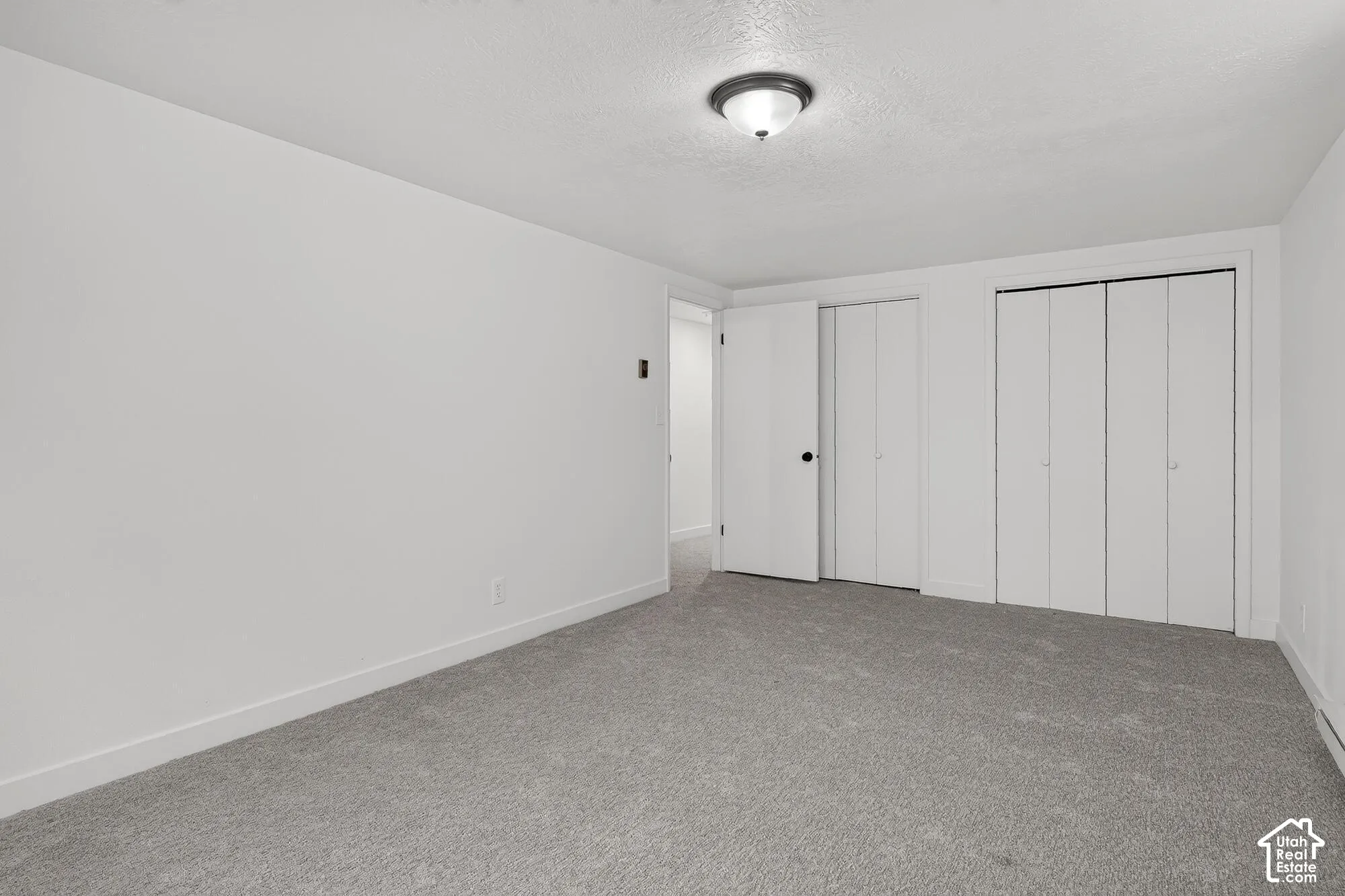 Neutral-toned wall-to-wall carpeting, flush-mount ceiling lighting, and dual sets of bi-fold closet doors
