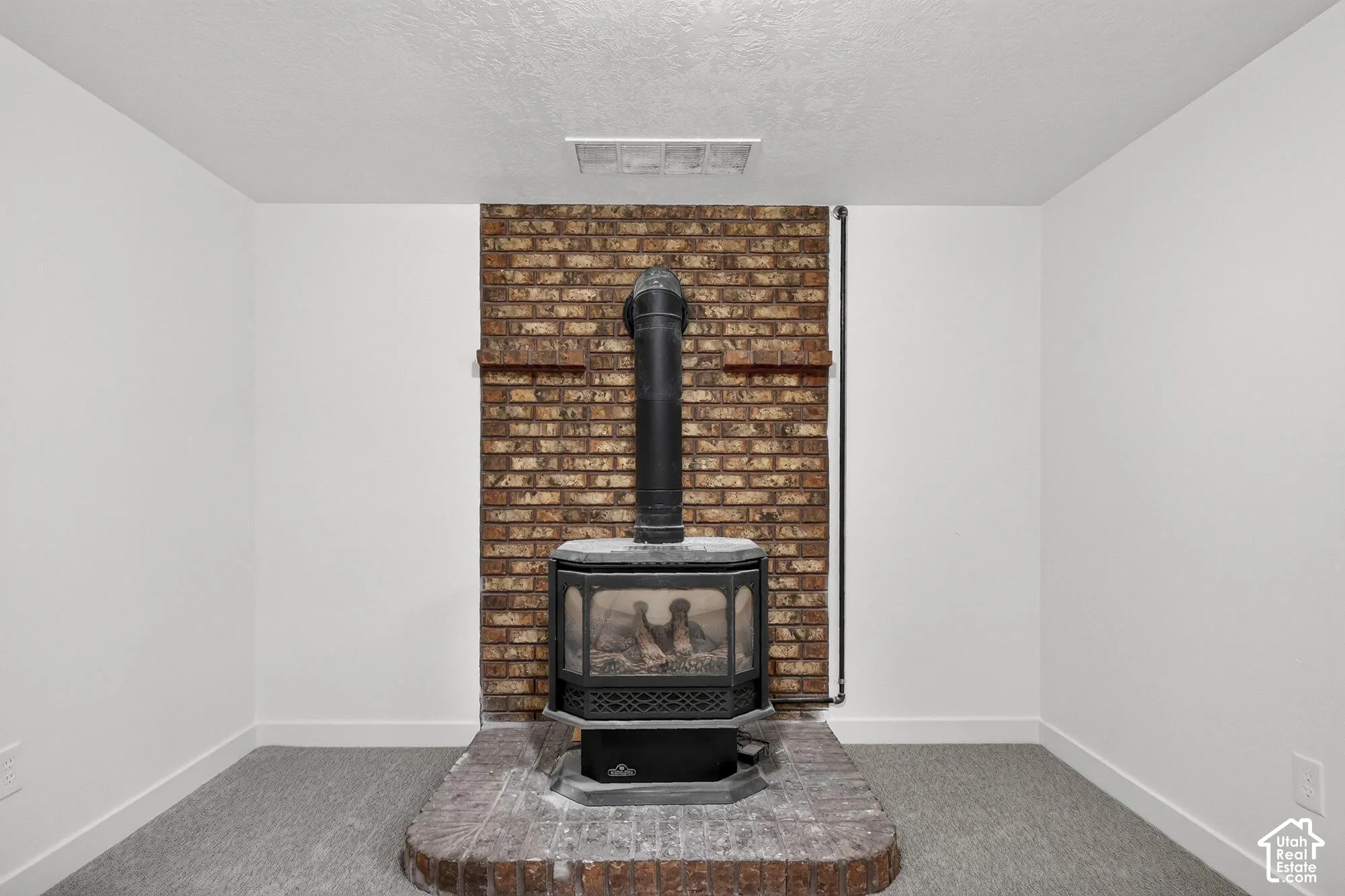 Brick hearth featuring a freestanding wood-burning stove and full-height decorative brick accent wall