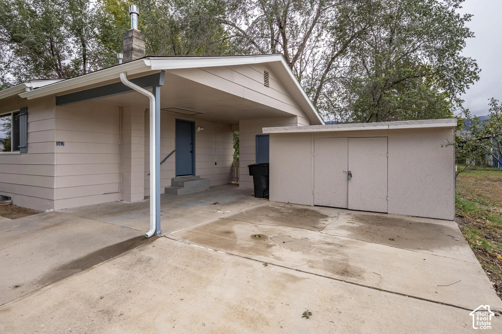 Exterior featuring horizontal siding, a covered carport, a stone chimney, and an attached exterior storage shed