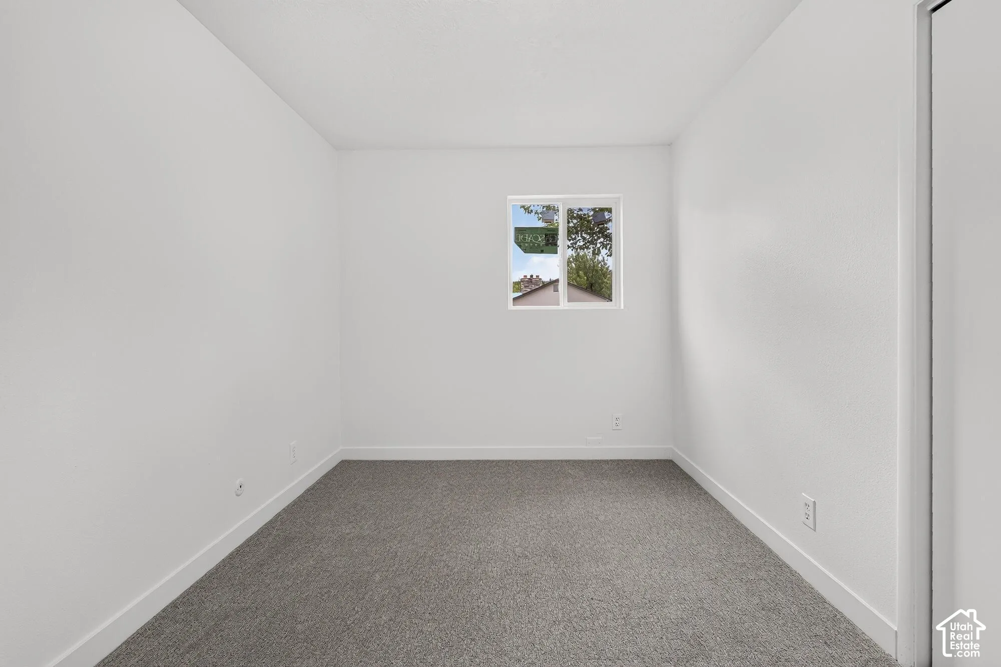 Neutral-toned wall-to-wall carpeting, crisp white walls, and a single-pane sliding window