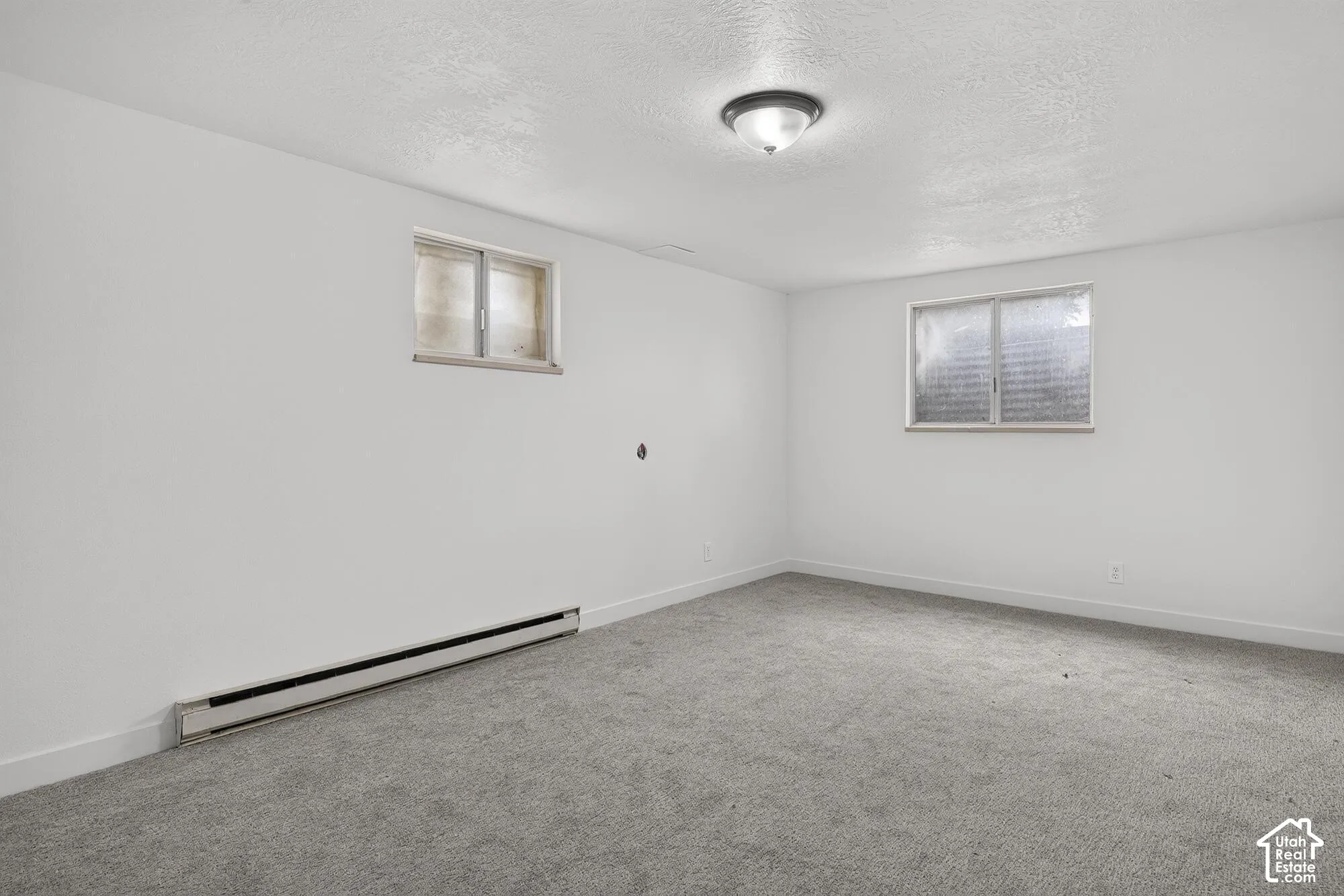 Neutral interior room featuring wall-to-wall carpeting, white walls, flush-mount lighting, and dual slider windows