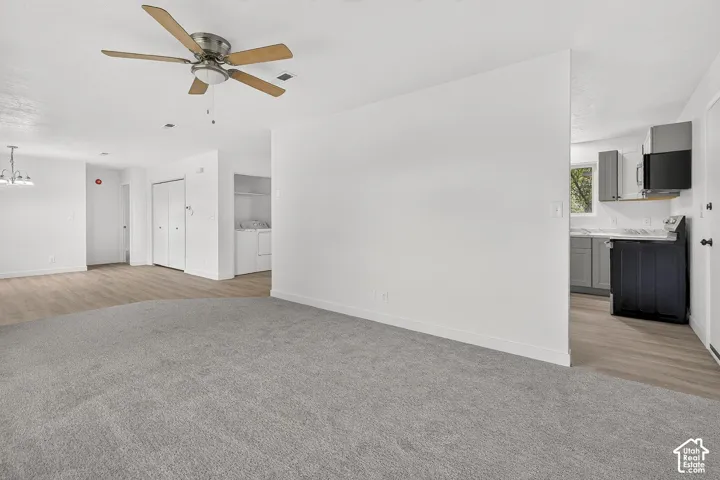 Neutral-toned wall-to-wall carpeting, wood-finish flooring, ceiling fan with light kit, and shaker-style cabinetry