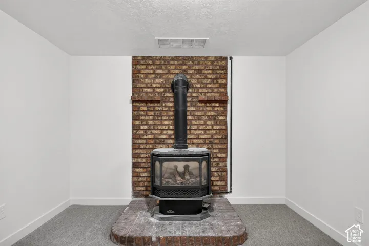 Brick hearth featuring a freestanding wood-burning stove and full-height decorative brick accent wall