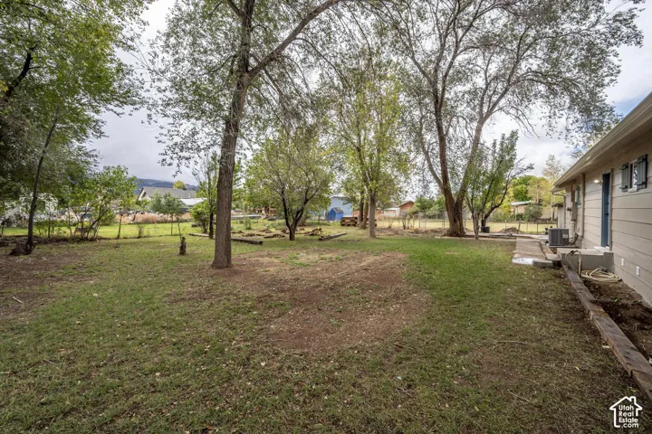 Expansive backyard featuring mature trees, a lawn area, and timber edging