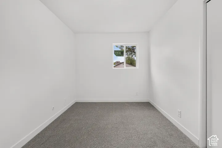 Neutral-toned wall-to-wall carpeting, crisp white walls, and a single-pane sliding window