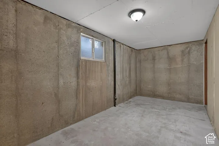 Concrete wall construction featuring a dual-pane sliding window, exposed vertical piping, and a flush-mount ceiling light fixture
