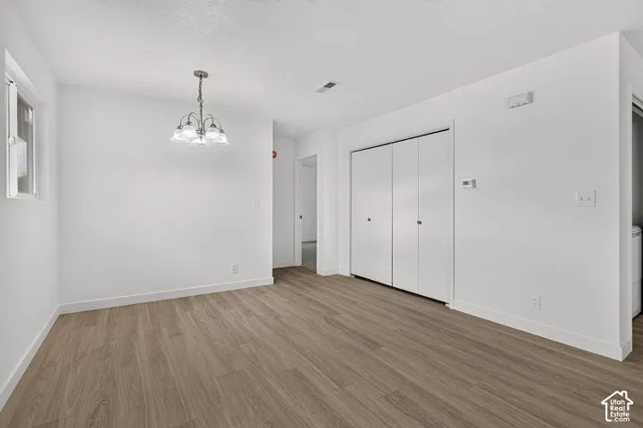 Interior space featuring wood-finish flooring, a multi-arm chandelier, and white wall finishes with double-door built-in closet storage