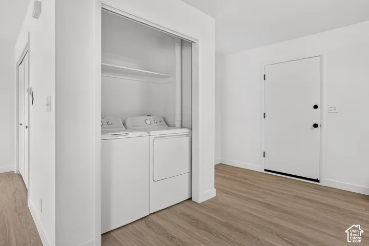 Laundry closet featuring built-in shelving, wood-finish flooring, and a single-panel interior door