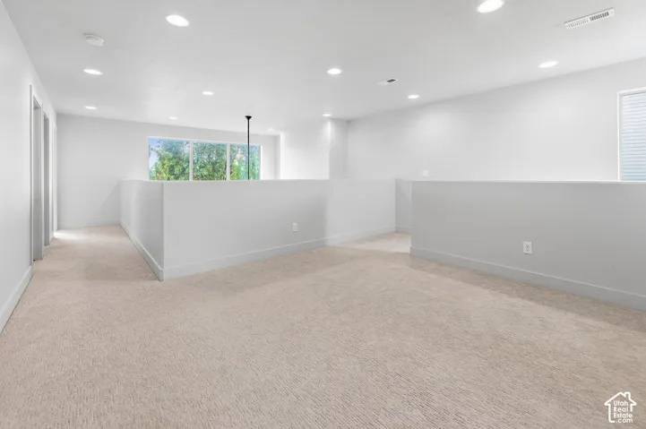 Open-concept space featuring wall-to-wall carpeting, recessed ceiling lighting, and expansive windows