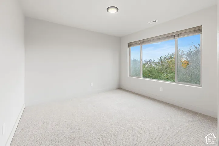 Interior room featuring neutral wall paint, wall-to-wall carpeting, a large picture window, and a flush-mount ceiling light fixture