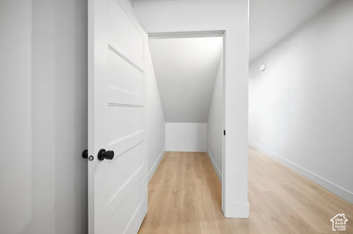 Interior storage space featuring wood-finish flooring, a four-panel door, and matte black hardware