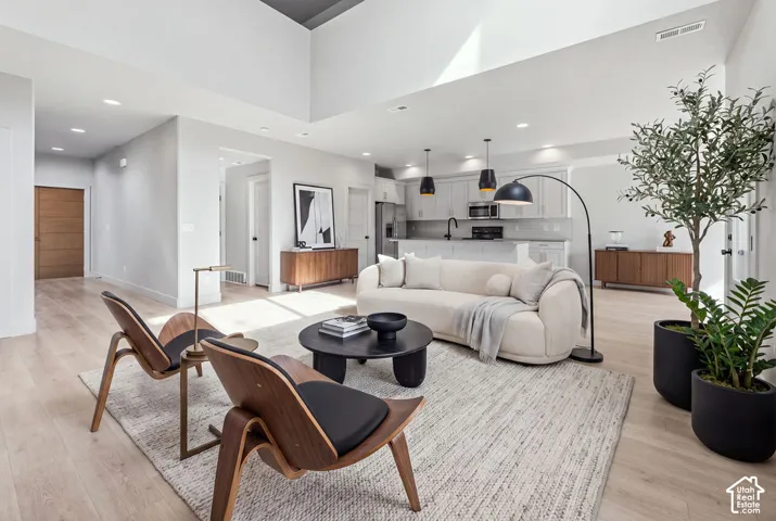 Open-concept interior featuring vaulted ceilings, wood-finish flooring, recessed lighting, and kitchen cabinetry with a central island