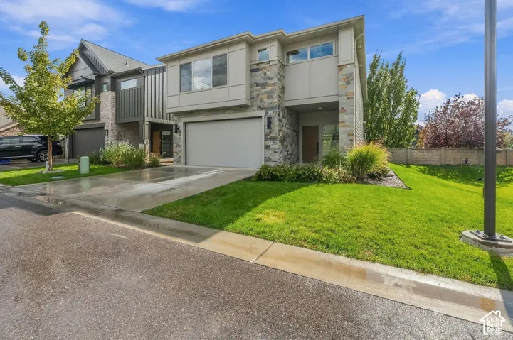 Two-story exterior featuring stone veneer accents, horizontal siding, attached garage, and manicured landscaping