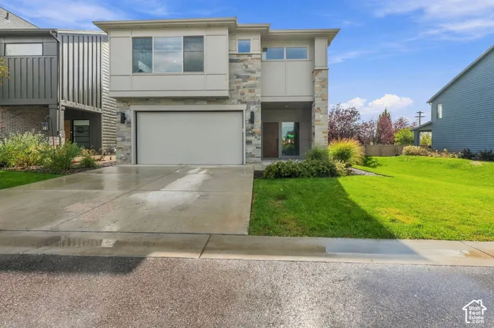 Two-story exterior featuring stone veneer accents, horizontal siding, attached two-car garage, concrete driveway, and front landscaping