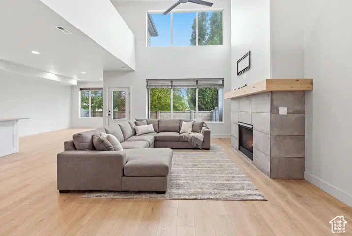 Vaulted ceilings, large-format concrete fireplace surround with a natural wood mantel, wood-finish flooring, and expansive windows