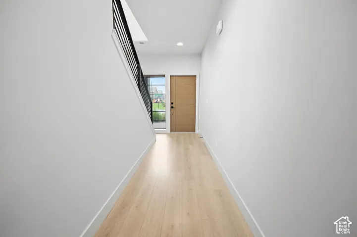 Entryway featuring wood-finish flooring, a solid core wood-finish door, and a staircase with a matte black metal railing