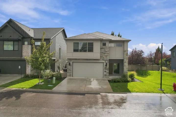 Two-story exterior featuring stone veneer accents, composite shingle roofing, horizontal siding, attached two-car garage, and concrete driveway