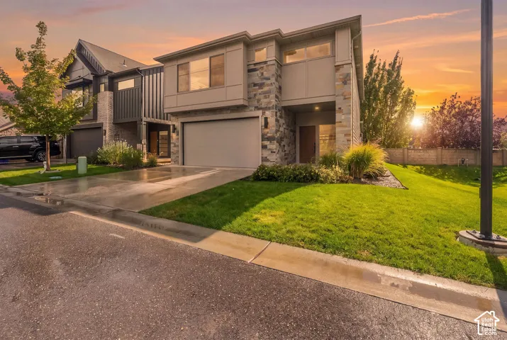 Two-story exterior featuring multi-textured siding, stone veneer accents, an attached two-car garage, and a concrete driveway