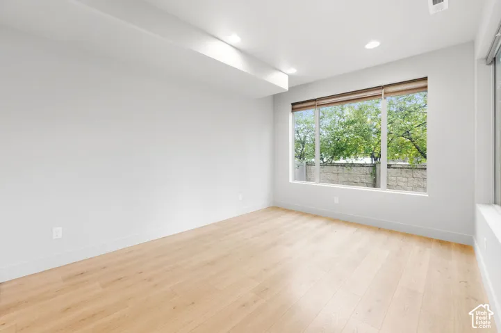 Neutral-toned interior featuring wood-finish flooring, recessed lighting, and a large picture window with light-filtering blinds