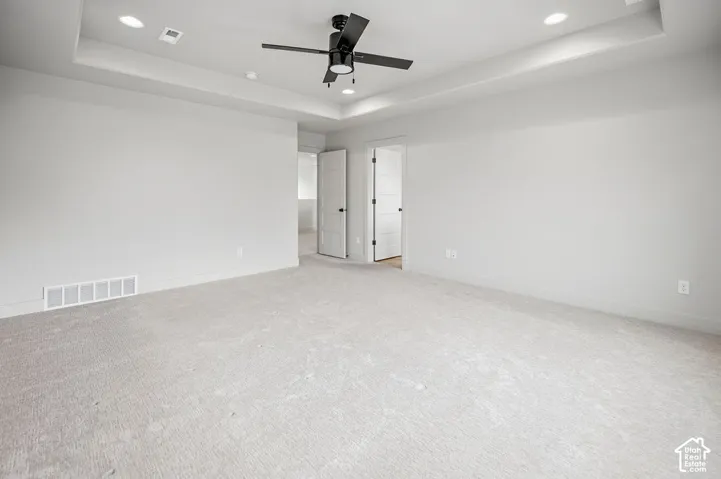 Tray ceiling with recessed lighting, central ceiling fan, neutral wall-to-wall carpeting, and interior doors with matte black hardware