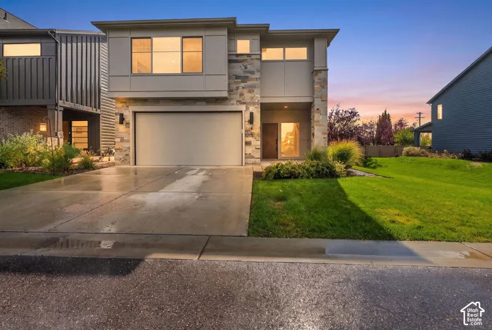 Contemporary multi-level exterior featuring stacked stone accents, vertical panel siding, a concrete driveway, and an attached two-car garage
