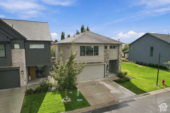 Exterior featuring light siding, stone veneer accents, an attached two-car garage, and concrete driveway
