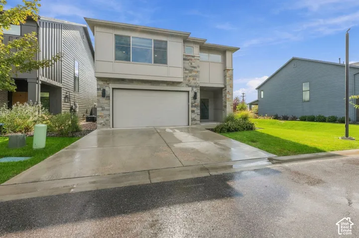 Two-story exterior featuring stone veneer accents, panel siding, a concrete driveway, a double-car garage, and an inset entry