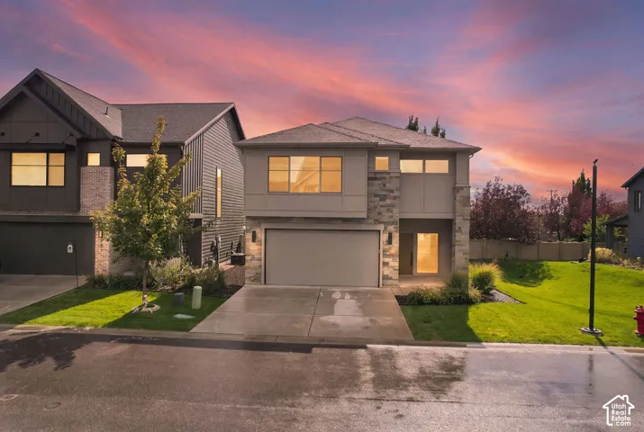 Contemporary two-story exterior featuring stone veneer accents, multi-pane windows, horizontal siding, and a double-car garage