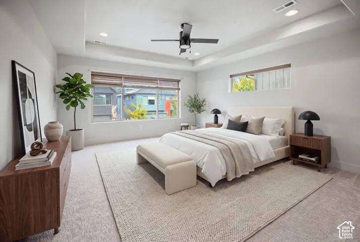 Tray ceiling featuring recessed lighting and a central ceiling fan, large windows, and neutral carpeting