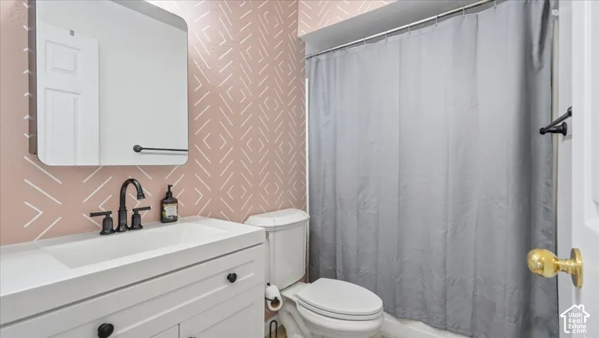 Bathroom featuring a white vanity with an integrated sink, matte black faucet, wall-mounted mirror, and patterned accent wall