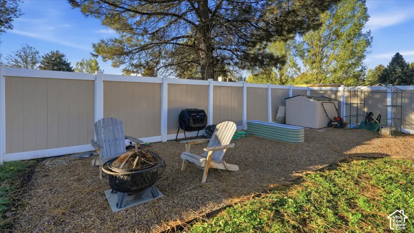 Backyard featuring a full-height vinyl privacy fence, gravel ground cover, and a raised metal garden bed