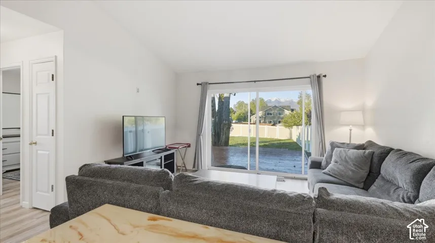 Vaulted ceiling featuring sliding glass doors with access to the patio, mountain scenery, and wood-finish flooring