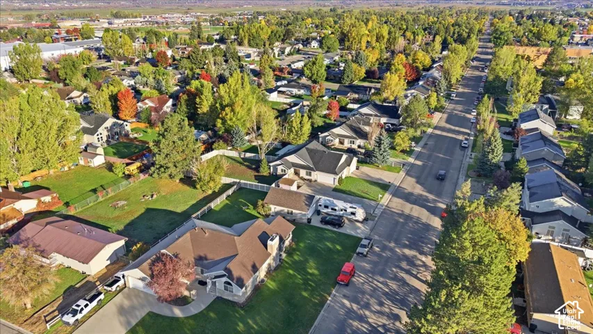 Aerial perspective featuring a multi-gabled roofline, brick-accented exterior, paved driveway, attached garage, and landscaped lot
