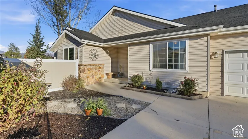 Exterior featuring light-toned horizontal siding, stone veneer accents, a covered entrance, and a concrete driveway leading to an attached garage